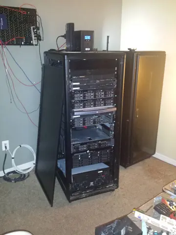 Dec 2016. The rack in its corner, a pegboard of network gear on the wall above.