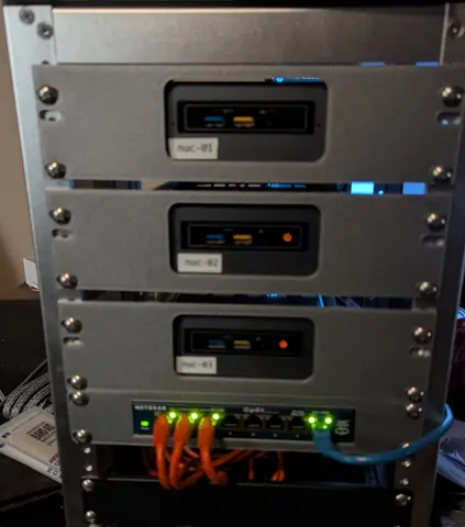 Apr 2026. The NUC minilab it replaced, photographed the same day: nuc-01 to nuc-03 (bought on eBay in June 2022) and a Netgear gigabit switch in an 8U 10-inch rack. It ran the k3s cluster in 2025 and has since been handed down to my son.